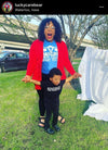 A woman in a red cardigan and blue Planned Parenthood t-shirt stands behind a young child in a black t-shirt that reads Nevertheless She Persisted, both wearing union labor apparel with their arms outstretched.