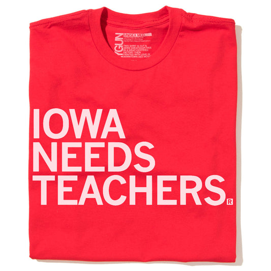 Red RAYGUN t-shirt with the text IOWA NEEDS TEACHERS printed in large white letters.