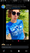 A person wearing patterned sunglasses and a sweatshop-free, bright blue t-shirt that says Get your own then tell me what to do.