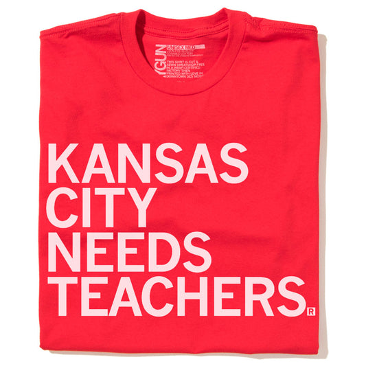 A red RAYGUN t-shirt with the white text KANSAS CITY NEEDS TEACHERS printed on the front.