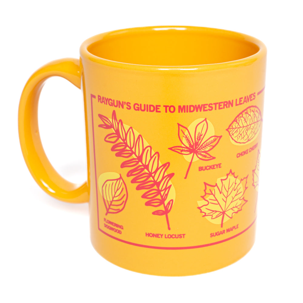 An 11 oz RAYGUN mug featuring a Midwestern Leaves illustration with drawings and labels for honey locust, buckeye, choke cherry, flowering dogwood, and sugar maple leaves.