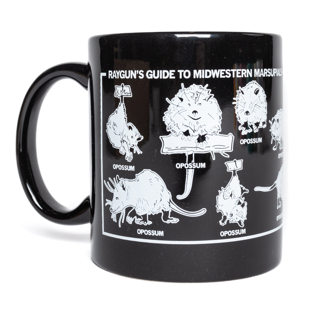An 11 oz black mug featuring white illustrations of opossums with the text RAYGUNS GUIDE TO MIDWESTERN MARSUPIALS.