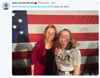 Elizabeth Warren stands with a smiling supporter wearing a Nasty Women T-shirt in front of an American flag.