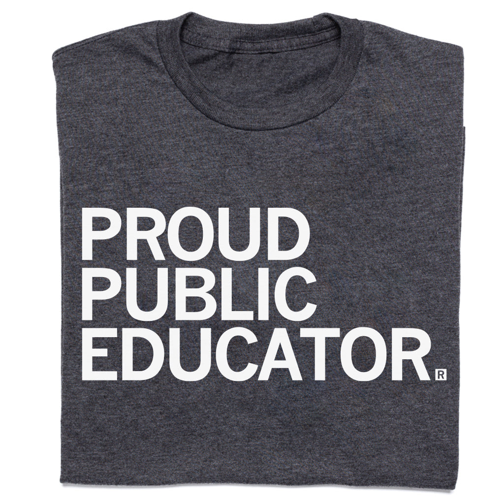 A folded charcoal t-shirt with white text that reads "Proud Public Educator"