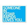 Blue RAYGUN sign with white text that reads, SOMEONE IN CEDAR RAPIDS LOVES YOU.