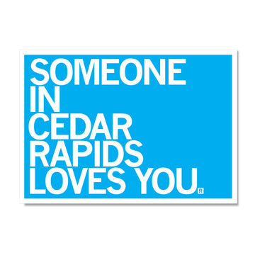 Blue RAYGUN sign with white text that reads, SOMEONE IN CEDAR RAPIDS LOVES YOU.