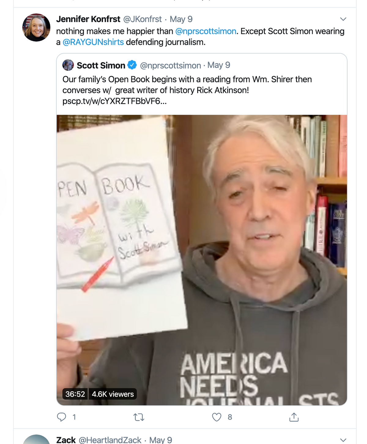 Scott Simon holds up a copy of Open Book while wearing a gray shirt that says America Needs Journalists.