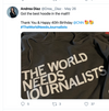A close-up of a union-made grey pullover hoodie with the text THE WORLD NEEDS JOURNALISTS printed in white letters.