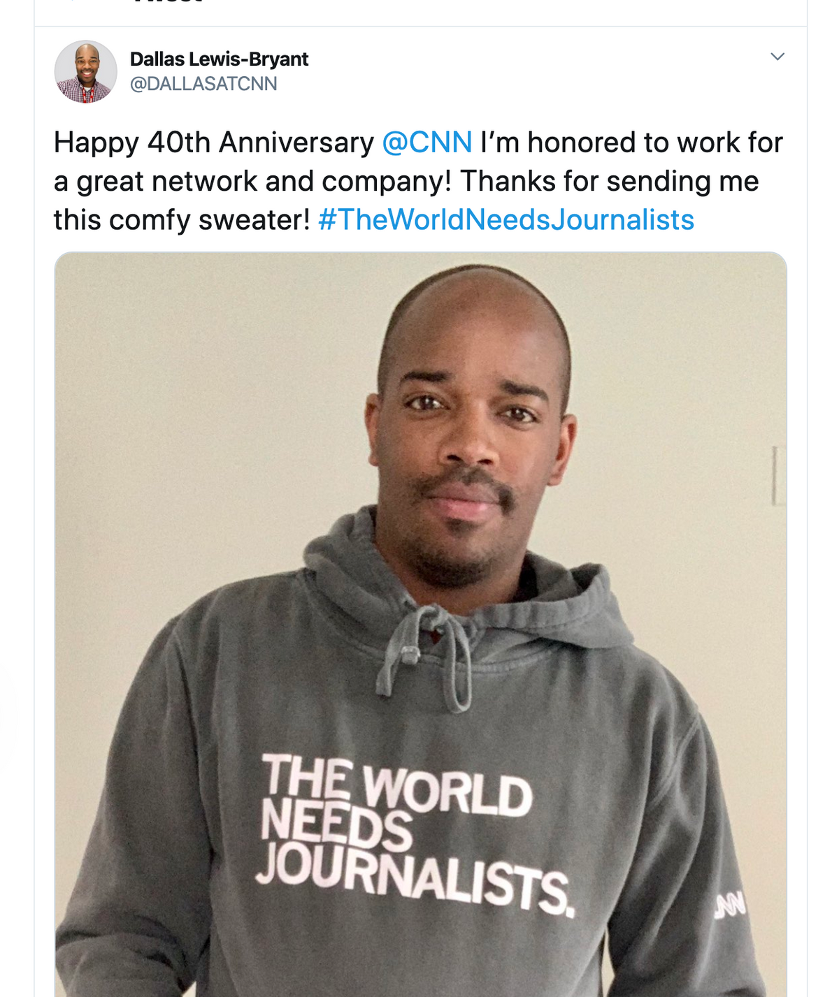 Dallas Lewis-Bryant wearing a union-made grey pullover hoodie with the text THE WORLD NEEDS JOURNALISTS.