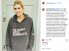 A woman wearing a union made, dark grey pullover hoodie that reads THE WORLD NEEDS JOURNALISTS with a small CNN logo on the sleeve.