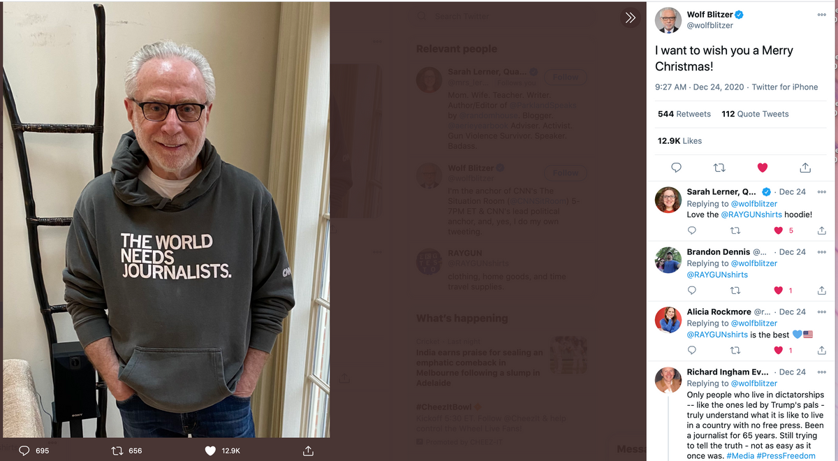 Wolf Blitzer wearing a dark gray union made pullover hoodie that reads THE WORLD NEEDS JOURNALISTS in white text.