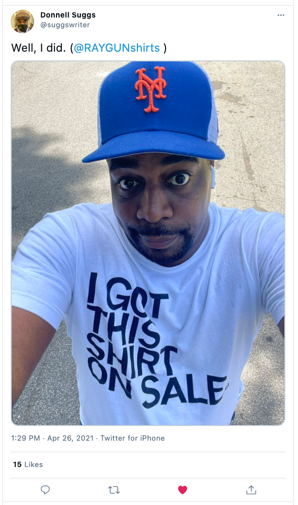 A person wearing a blue New York Mets baseball cap and a white screen print t-shirt that says I GOT THIS SHIRT ON SALE.