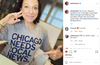 A woman smiles and gestures toward her grey t-shirt that reads, CHICAGO NEEDS LOCAL NEWS, a design for Block Club Chicago.
