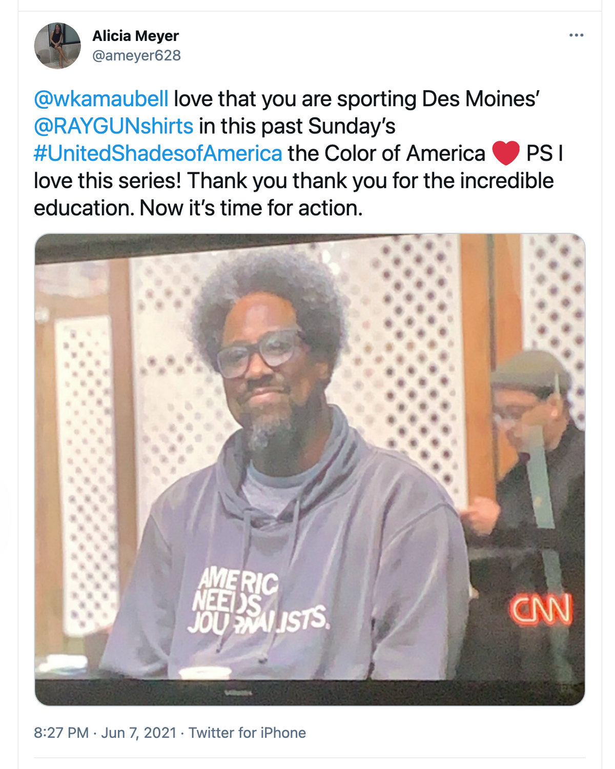 A man with glasses and an afro wears a gray Pigment Black Pullover Hoodie that says AMERIC NEEDS JOURNALISTS while appearing on a television screen featuring a CNN logo.