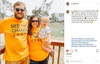 A family of three wears matching RAYGUN bee-themed shirts while standing on a wooden deck, with a father holding a baby in a yellow outfit next to a smiling mother.