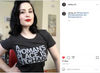 A person wearing a sweatshop-free grey t-shirt with the text A WOMANS PLACE IS IN CHARGE.