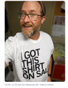 A man wearing glasses and a RAYGUN screen print t-shirt that says I GOT THIS SHIRT ON SALE smiles at the camera.
