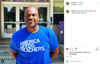 A smiling man wearing a union made T-shirt that reads America Needs Teachers stands in front of a school entrance to show his support for public education.