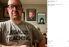 A man in glasses and a heather grey, union-made t-shirt that reads LEGALIZE TEACHING stands in front of three framed posters featuring Johnny Cash, Ani DiFranco, and Robert Smith.