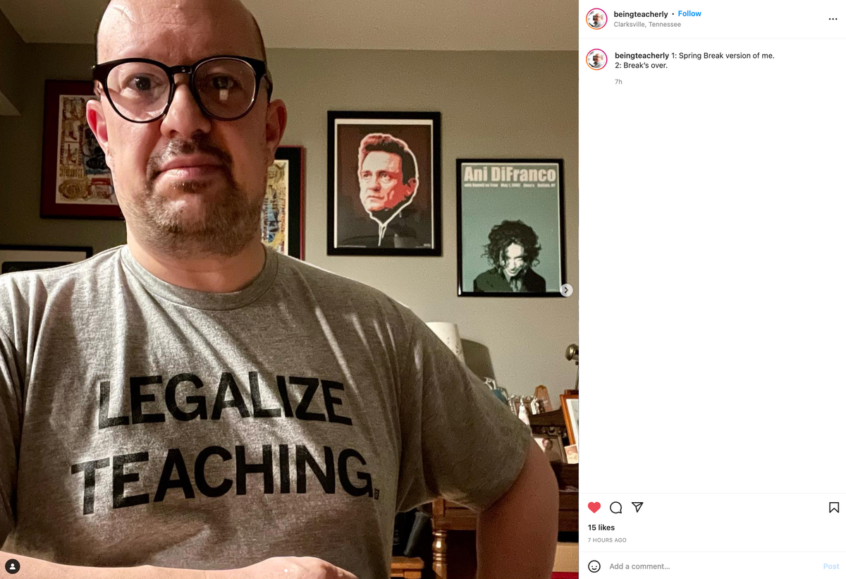 A man in glasses and a heather grey, union-made t-shirt that reads LEGALIZE TEACHING stands in front of three framed posters featuring Johnny Cash, Ani DiFranco, and Robert Smith.