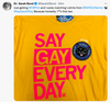 A yellow supportive pride apparel t-shirt with SAY GAY EVERY DAY in large pink font, featuring a circular black pin of a cat saying GAAAAAAAY!!! and a tag from THE GREATEST STORE IN THE UNIVERSE.
