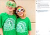 Two children wearing matching heather kelly green T-shirts that say Cedar Rapids: Magically Delicious and novelty glasses shaped like shamrocks and a rainbow.