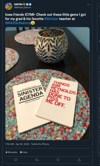 Two RAYGUN books titled Sinister Agenda and Things Kim Reynolds Has Done to Piss Me Off resting on a table.