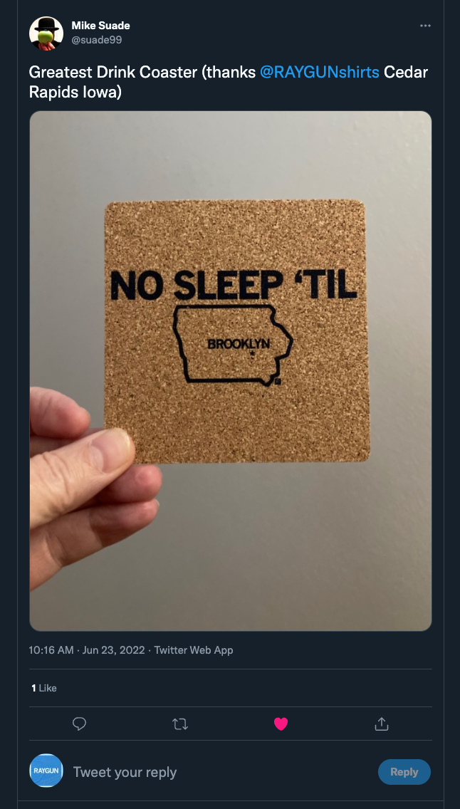 A hand holds a high-density cork coaster featuring an outline of Iowa with the word BROOKLYN inside and the text NO SLEEP TIL above it.
