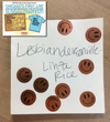A note on paper with a Lesbiandersonville contest flyer in the corner, decorated with several copper-colored smiley face stickers.