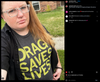 A person with red hair and glasses wearing a charcoal t-shirt that says DRAG SAVES LIVES in yellow lettering.