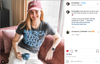A woman wearing a pink MOM hat and a dark, union-made T-shirt that says AMERICA NEEDS FEMALE LEADERS sits on a couch holding a blue mug.