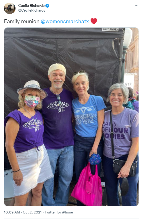 Four people posing for a photo, wearing sweatshop free, union labor shirts with purple and blue social justice slogans.