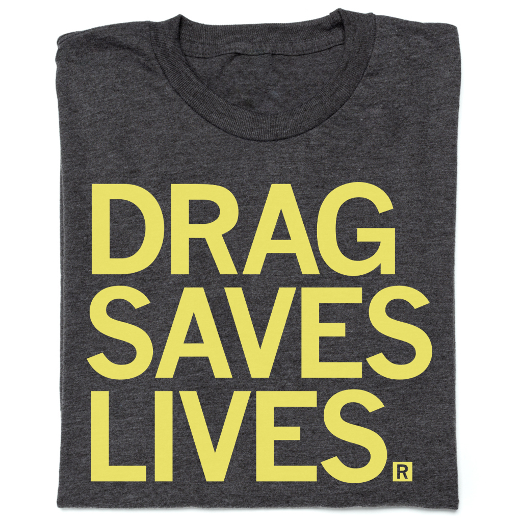 Folded charcoal T-shirt with the yellow text DRAG SAVES LIVES. printed on the front.