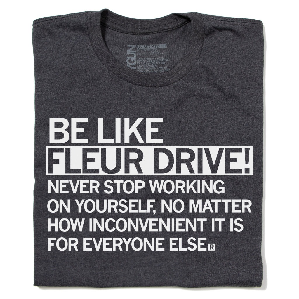 Charcoal gray RAYGUN inspirational t-shirt with white text that reads, BE LIKE FLEUR DRIVE! NEVER STOP WORKING ON YOURSELF, NO MATTER HOW INCONVENIENT IT IS FOR EVERYONE ELSE.