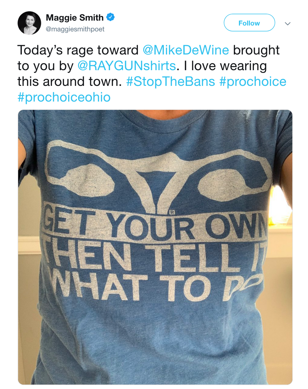 A person wearing a union labor blue t-shirt featuring a stylized uterus icon above the text: GET YOUR OWN THEN TELL IT WHAT TO DO.