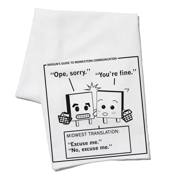 White RAYGUN kitchen towel featuring a cartoon titled Rayguns Guide to Midwestern Communication, showing two characters bumping into each other with the captions Ope, sorry and You’re fine, translated as Excuse me and No, excuse me.