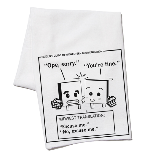 White RAYGUN kitchen towel featuring a cartoon titled Rayguns Guide to Midwestern Communication, showing two characters bumping into each other with the captions Ope, sorry and You’re fine, translated as Excuse me and No, excuse me.
