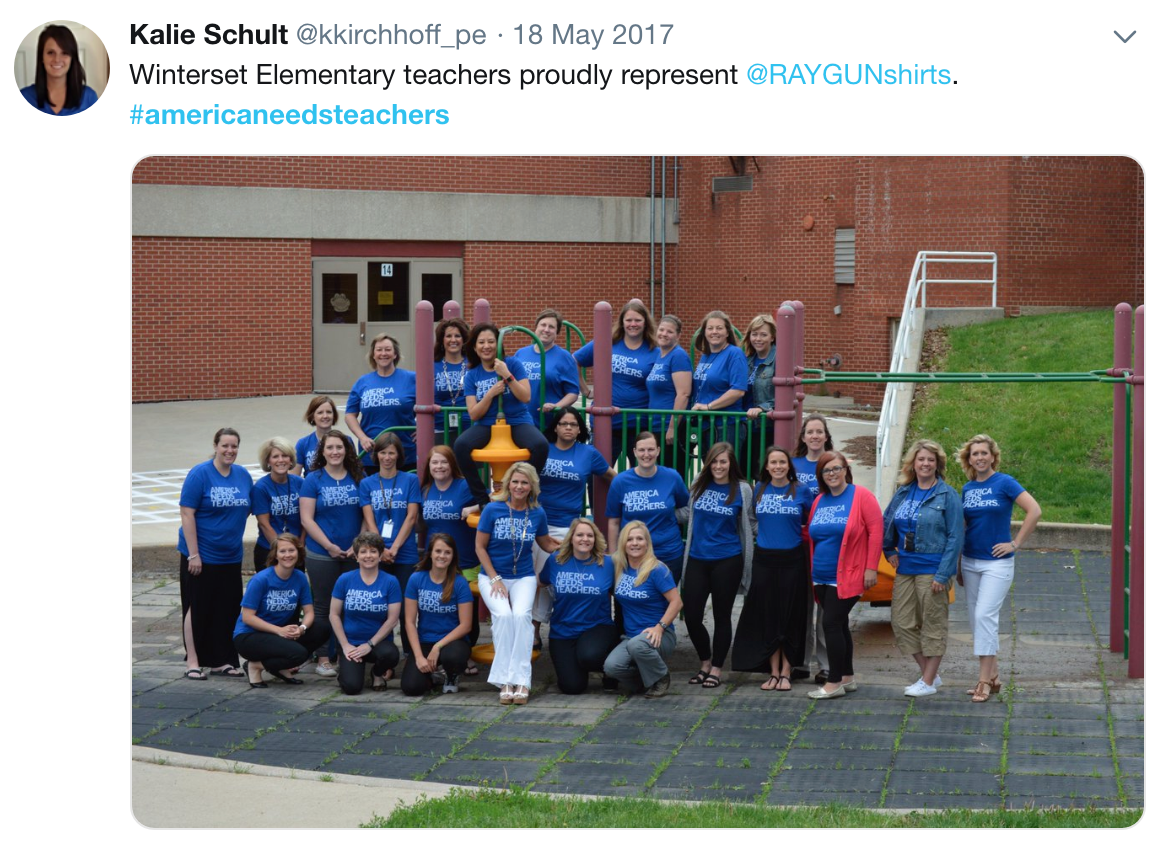 A group of teachers in matching blue America Needs Teachers t-shirts pose for a photo on a school playground to show their support for public education.