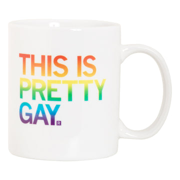 White ceramic Pretty Gay mug with the rainbow-colored text THIS IS PRETTY GAY. printed on the front.