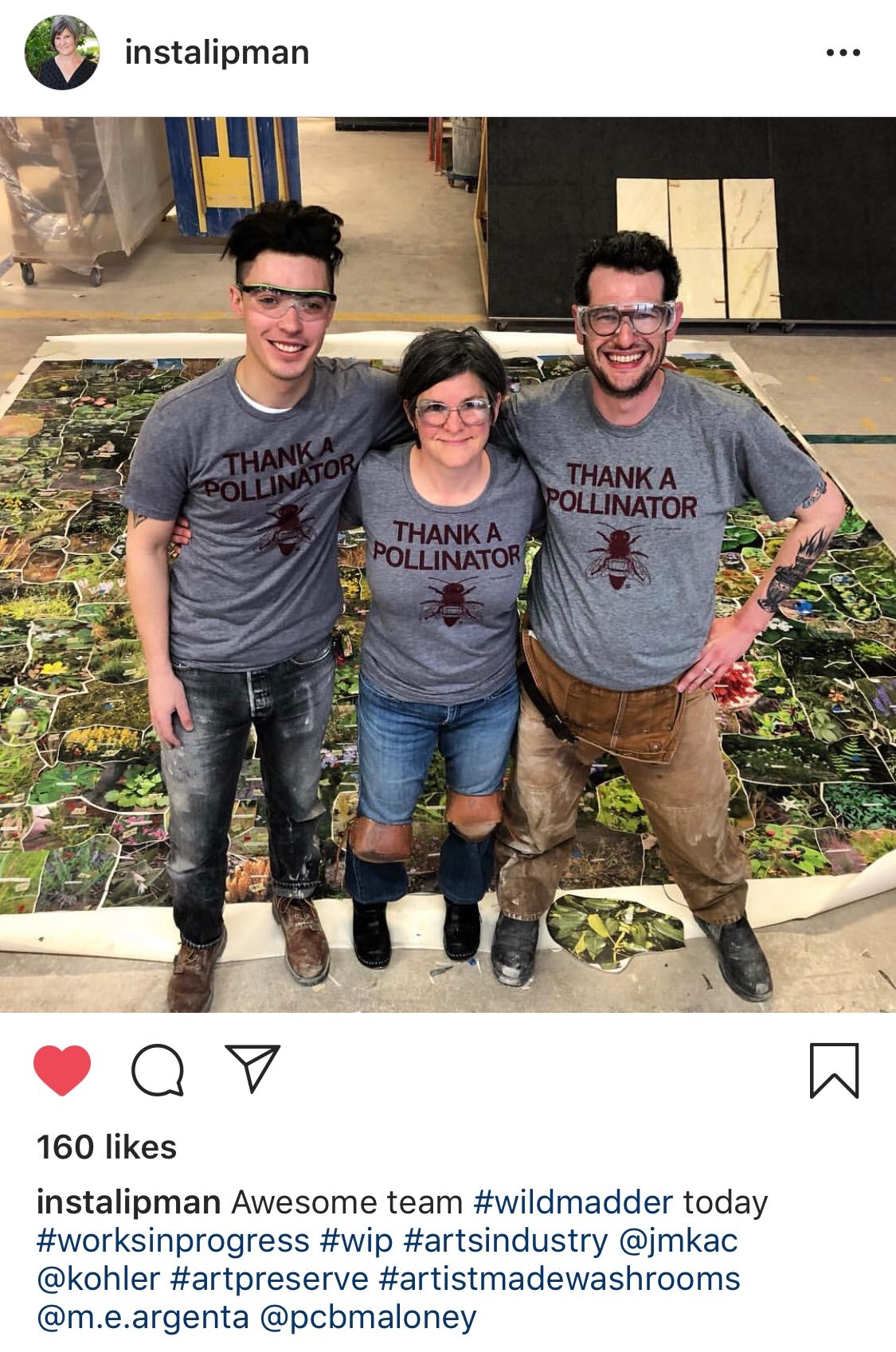 Three people wearing matching eco-friendly Thank a Pollinator t-shirts and safety glasses stand together on a large floor-covering printed with a forest garden motif.