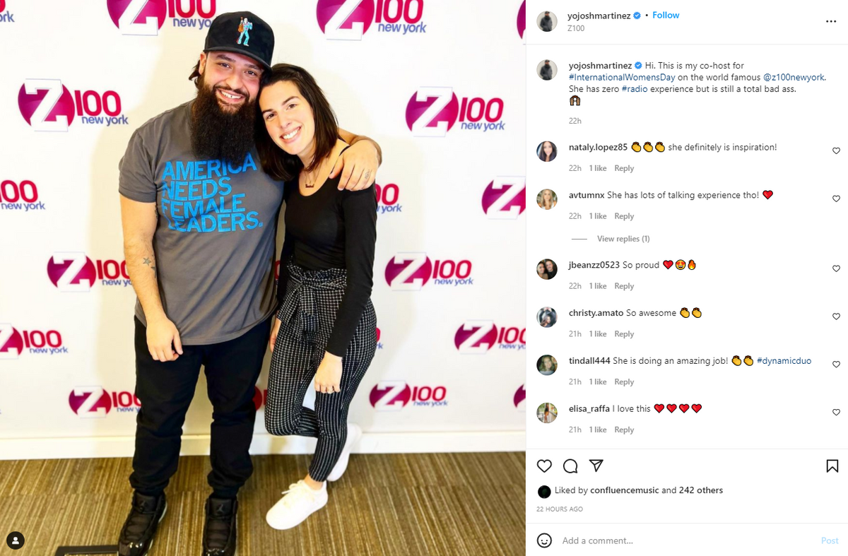 A woman in a union made t-shirt smiles with her arm around a man with a full beard and baseball cap, both standing in front of a Z100 New York logo backdrop.