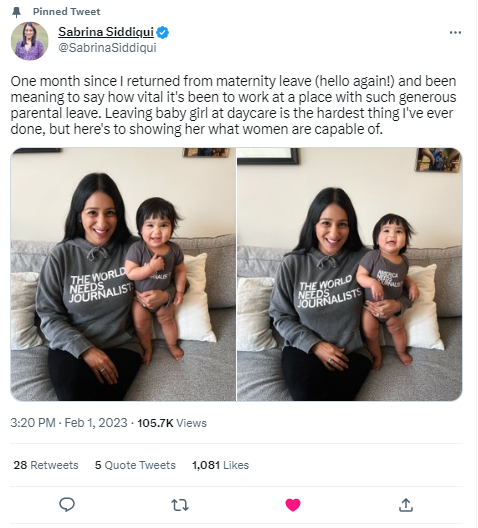 Sabrina Siddiqui sits on a sofa with her baby, both wearing matching gray pullover hoodies that say The World Needs Journalists.