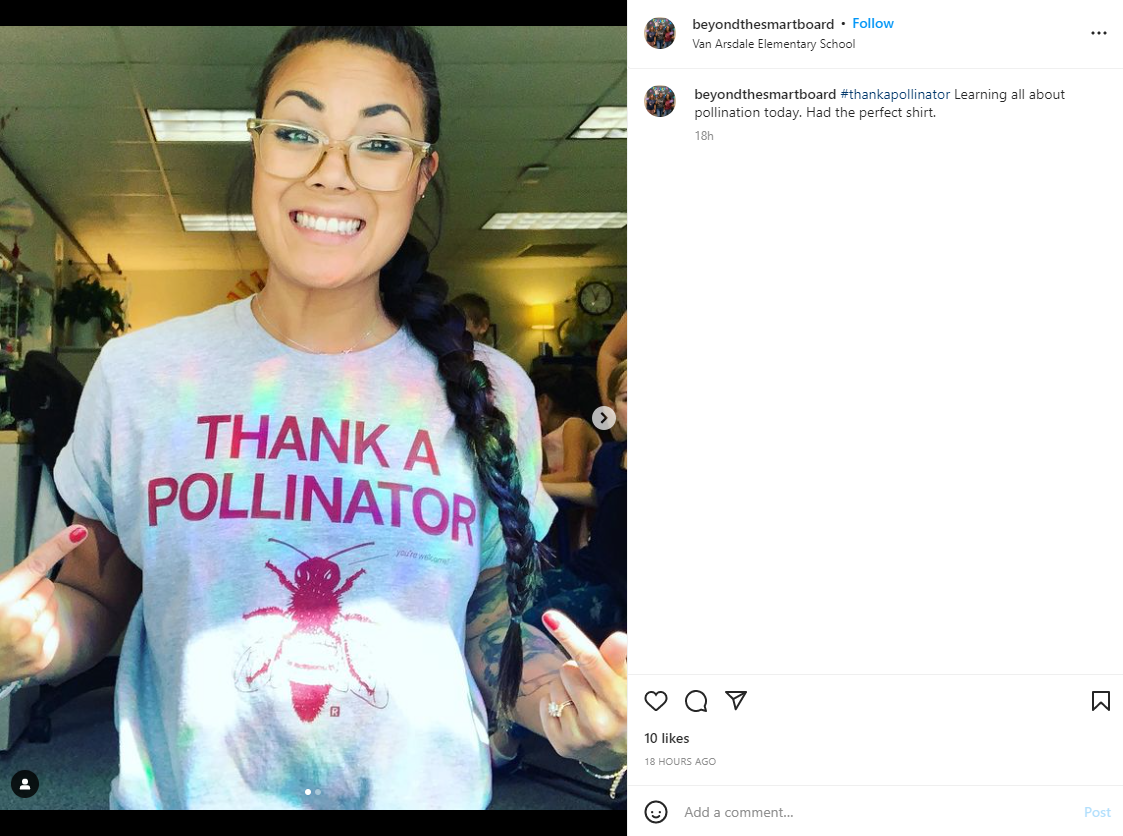 A woman smiling while wearing a grey, eco-friendly pollinator t-shirt that says THANK A POLLINATOR with an image of a bee.