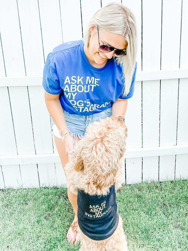 A smiling woman and her fluffy dog wearing matching RAYGUN dog shirts that say Ask me about my dog’s Instagram.