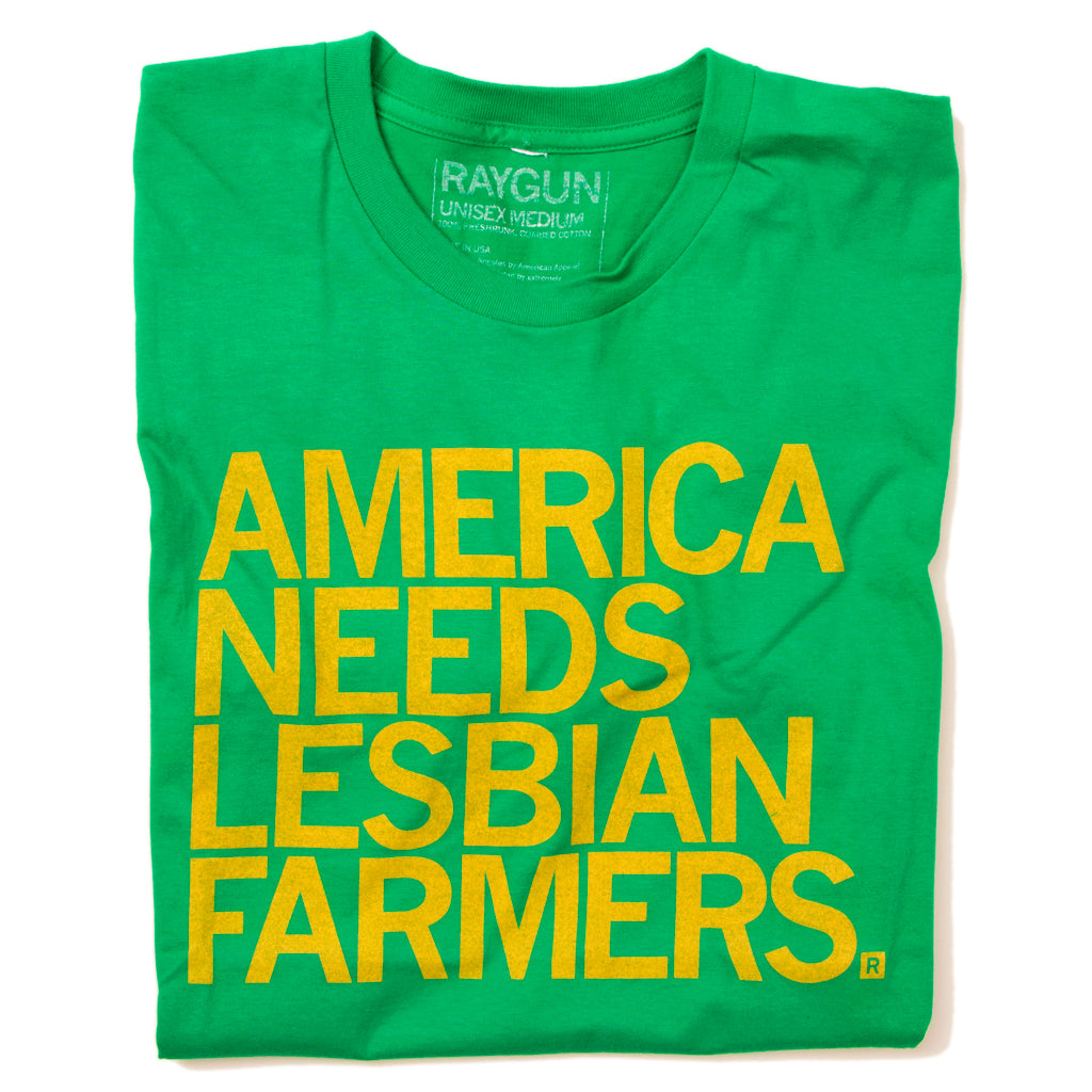A folded heather kelly green shirt with left aligned yellow text that says, "America Needs Lesbian Farmers"