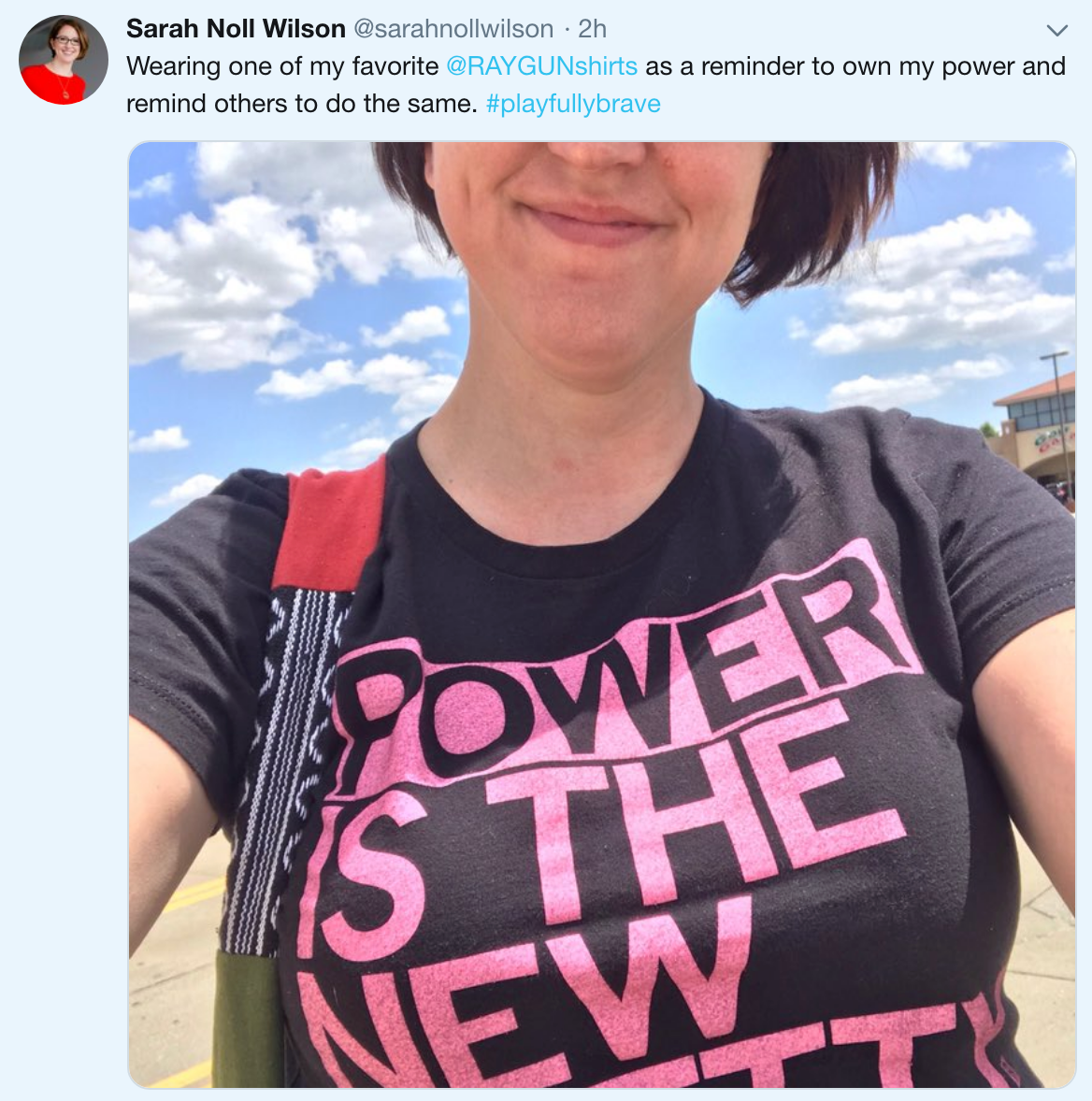 A woman wearing a black Union Labor t-shirt with the pink text POWER IS THE NEW PRETTY visible on the front.