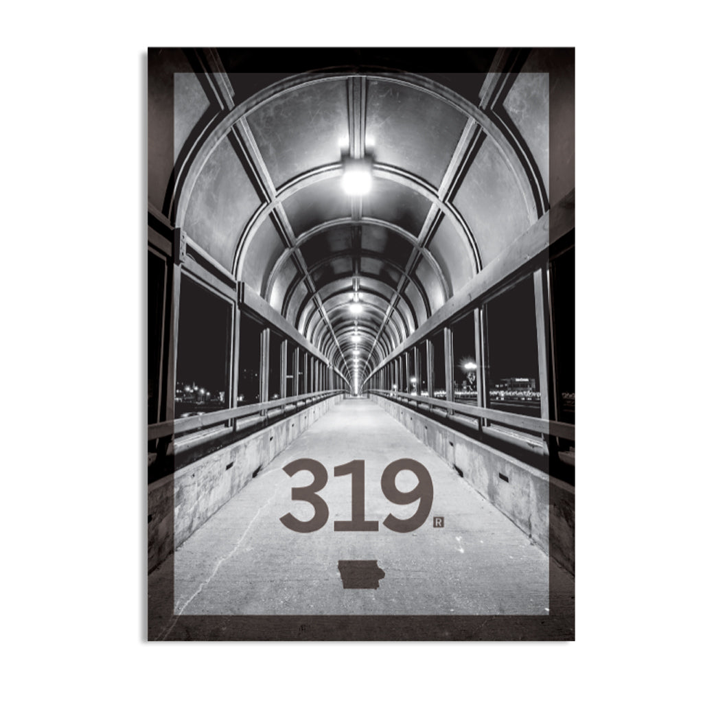 Black and white photo of a covered pedestrian bridge looking down a long, arched tunnel, with the 319 Iowa area code and the state’s shape printed in the foreground.