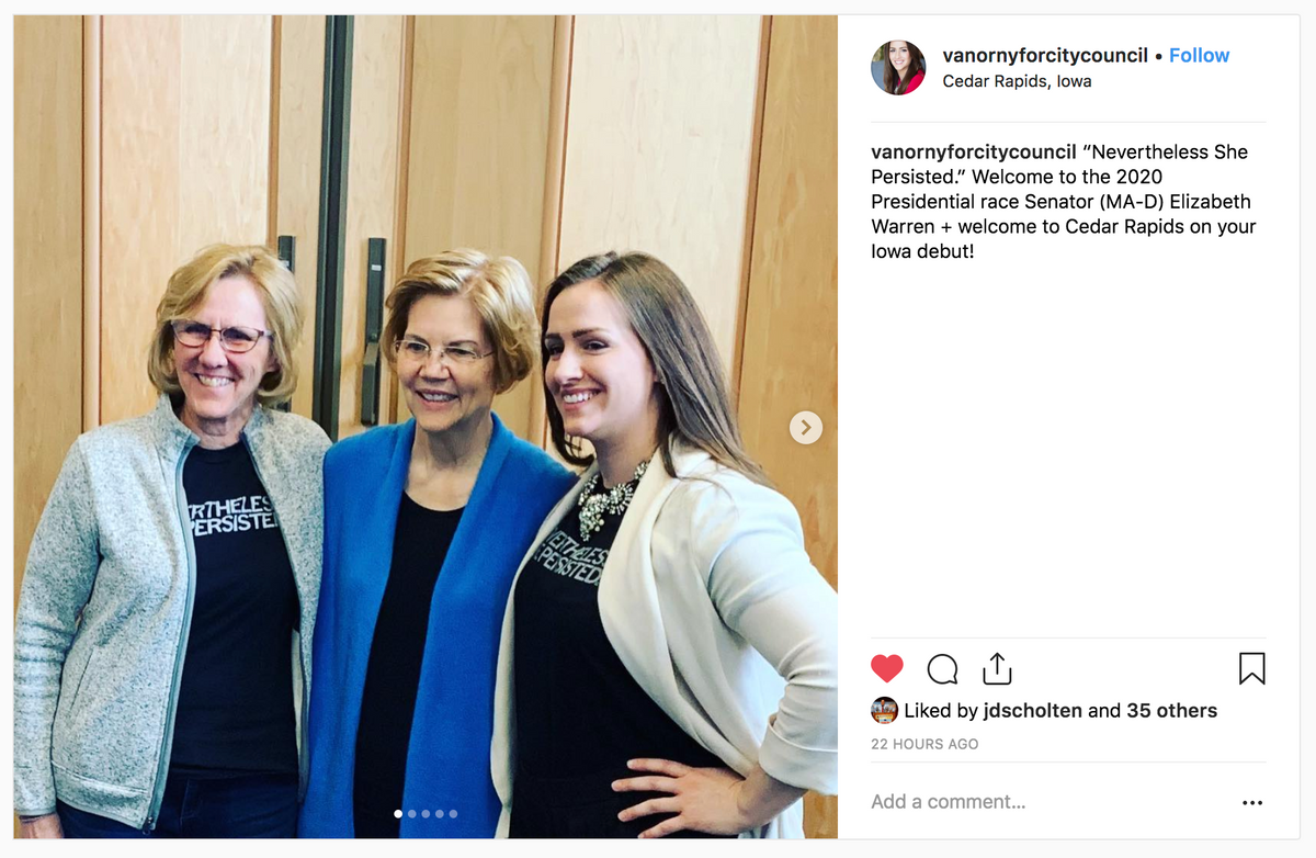 Elizabeth Warren stands between two women wearing black Nevertheless She Persisted feminist t-shirts.