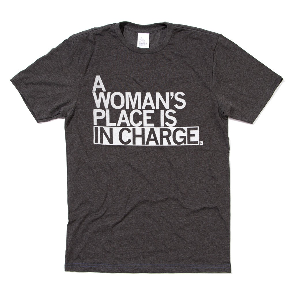 Charcoal t-shirt with left aligned white ink that reads "A Woman's Place Is In Charge"