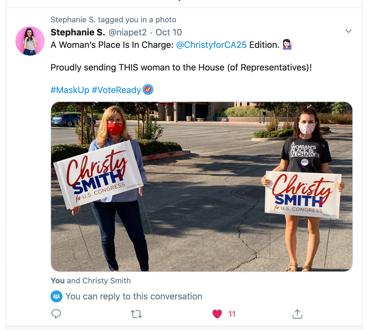 Two women standing outdoors in union-made clothing, each holding a sign that reads Christy Smith for U.S. Congress.